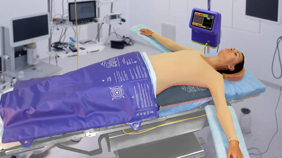 Patient on an operating room table receiving air-free conductive warming with a HotDog underbody mattress and warming blanket, controlled by the HotDog patient warming unit.